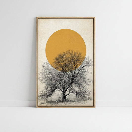 A framed minimalist art print featuring a large golden-yellow sun and a bare tree on a cream background, leaning against a white wall on a white floor.
