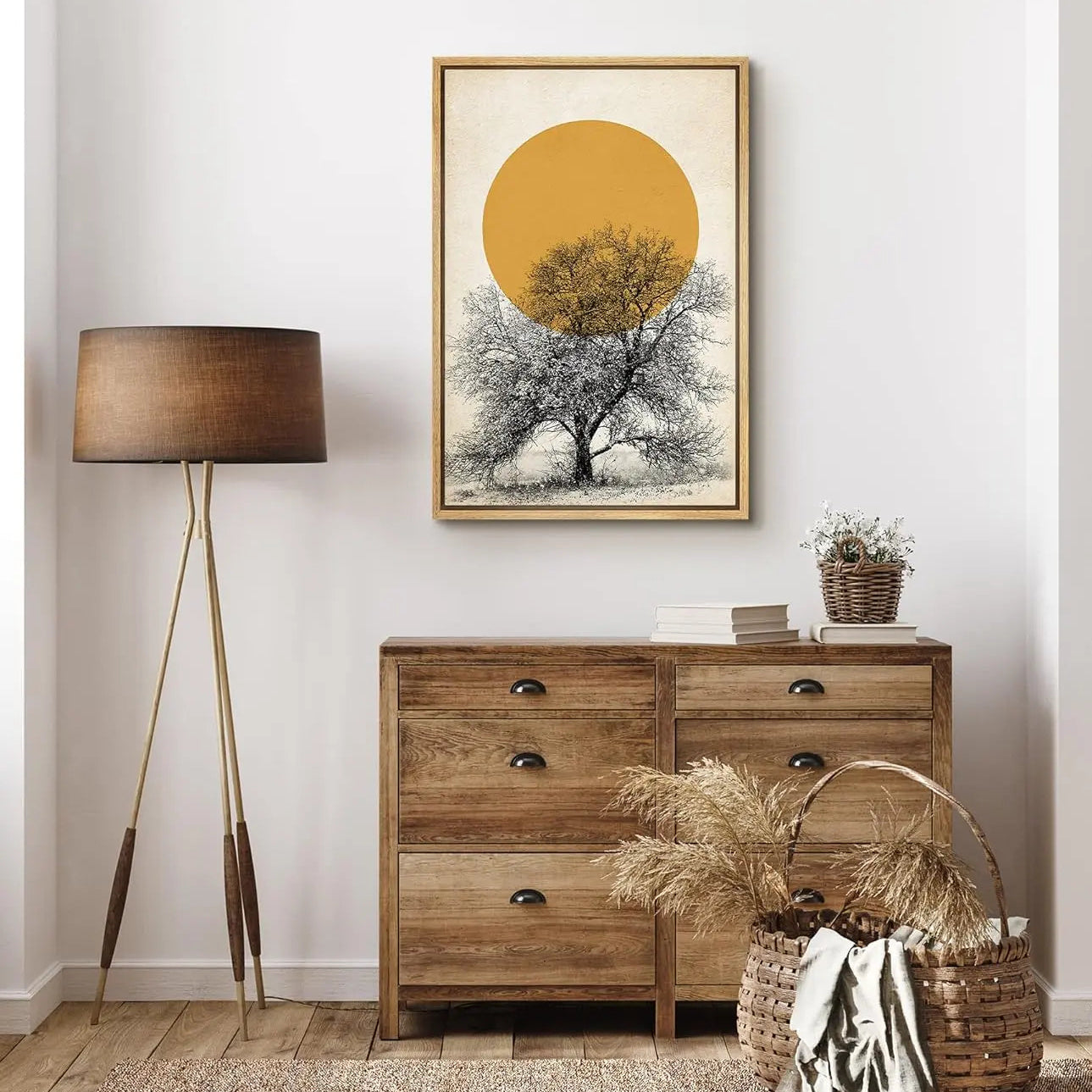 Wooden dresser with decorative items and a framed artwork of a tree and sun on a white wall.