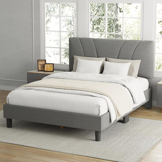 Gray upholstered bed with white bedding in a room with large windows.