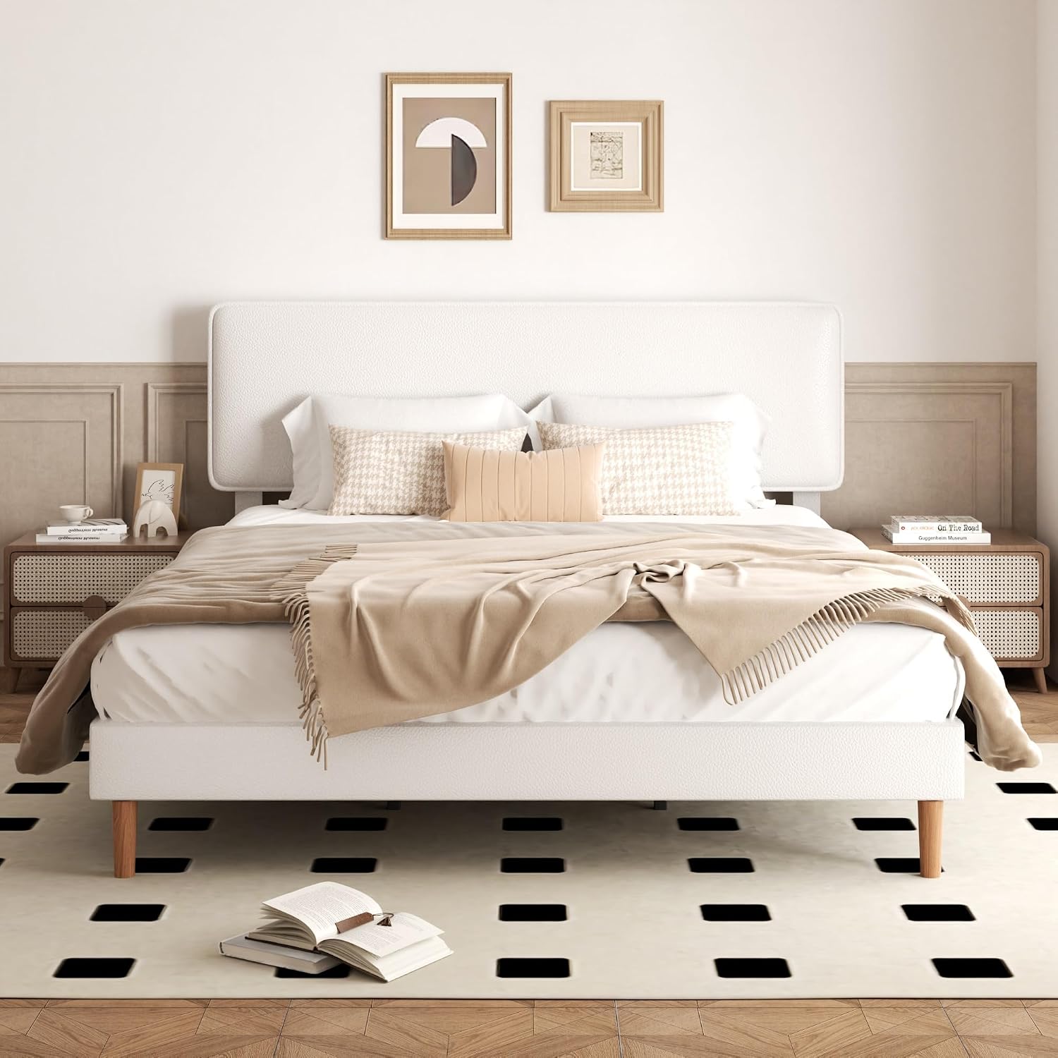 A modern white platform bed with a tall upholstered headboard, styled with beige and white bedding, wooden nightstands, framed wall art, and a black-and-white checkered rug in a neutral bedroom setting.