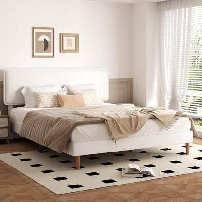 Modern bedroom with a white bed, beige blanket, and patterned rug.