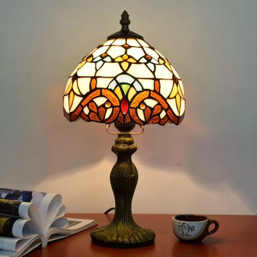 Tiffany-style table lamp with stained glass shade on a wooden surface.