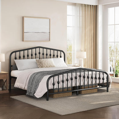 A black metal bed frame with decorative spindle-style headboard and footboard rails, shown in a styled bedroom setting with white bedding, a patterned throw blanket, a rug, and large windows with sheer curtains.