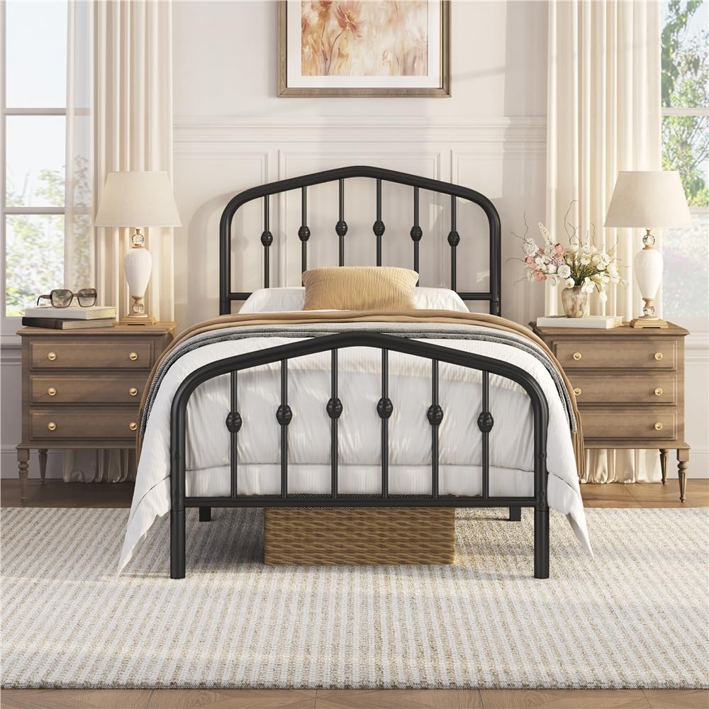 A black metal bed frame with an arched headboard and footboard, styled in a bright, symmetrical bedroom with wooden nightstands, lamps, and neutral bedding.