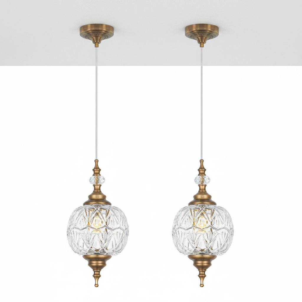 Two gold pendant lights with clear glass shades on a white background