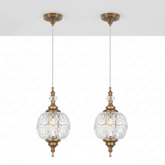 Two gold pendant lights with clear glass shades on a white background