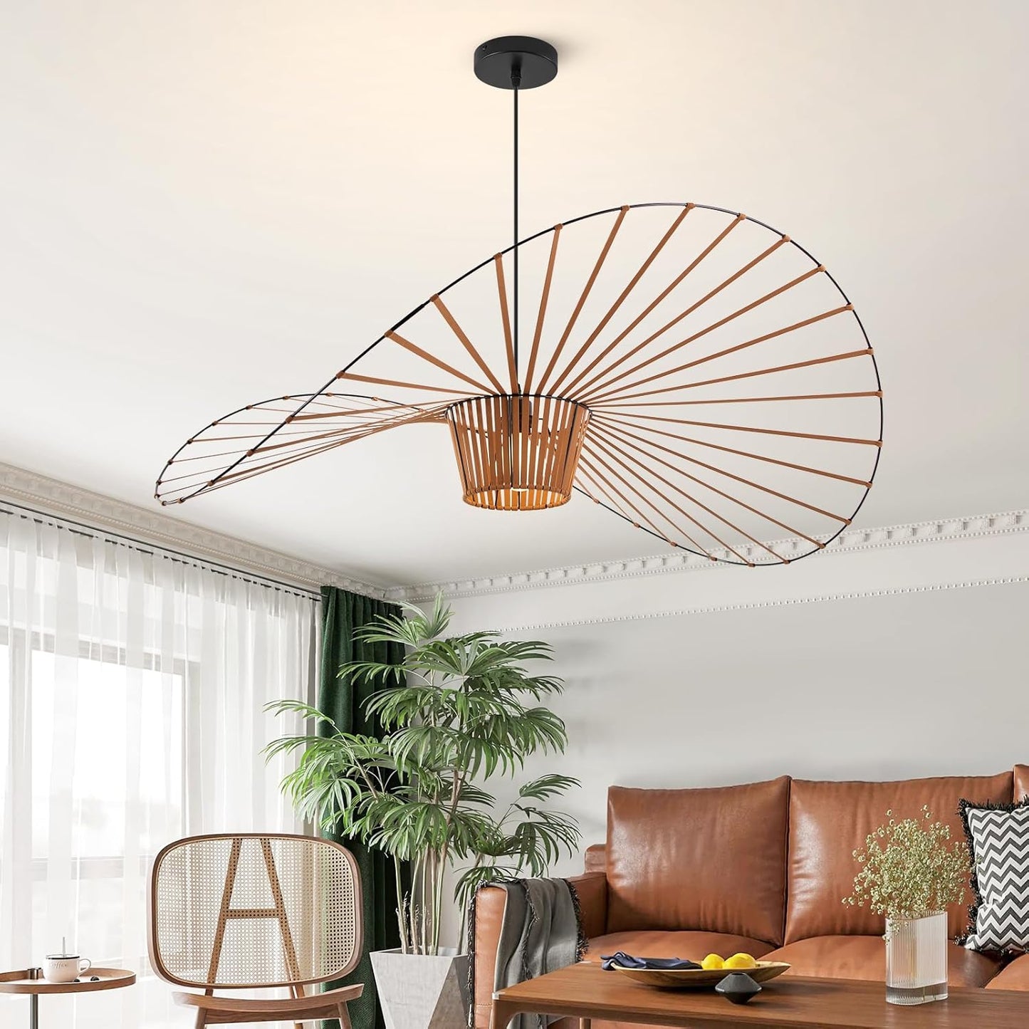 A modern spiral pendant light with a black metal frame and a woven natural-fiber shade, hanging in a bright living room above a brown leather sofa.