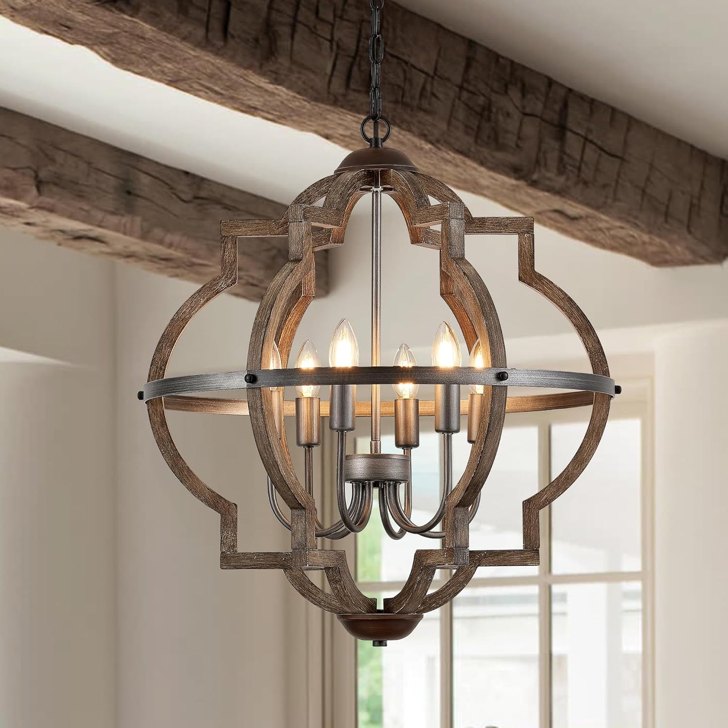 Wooden chandelier hanging in a room with wooden beams and a window.