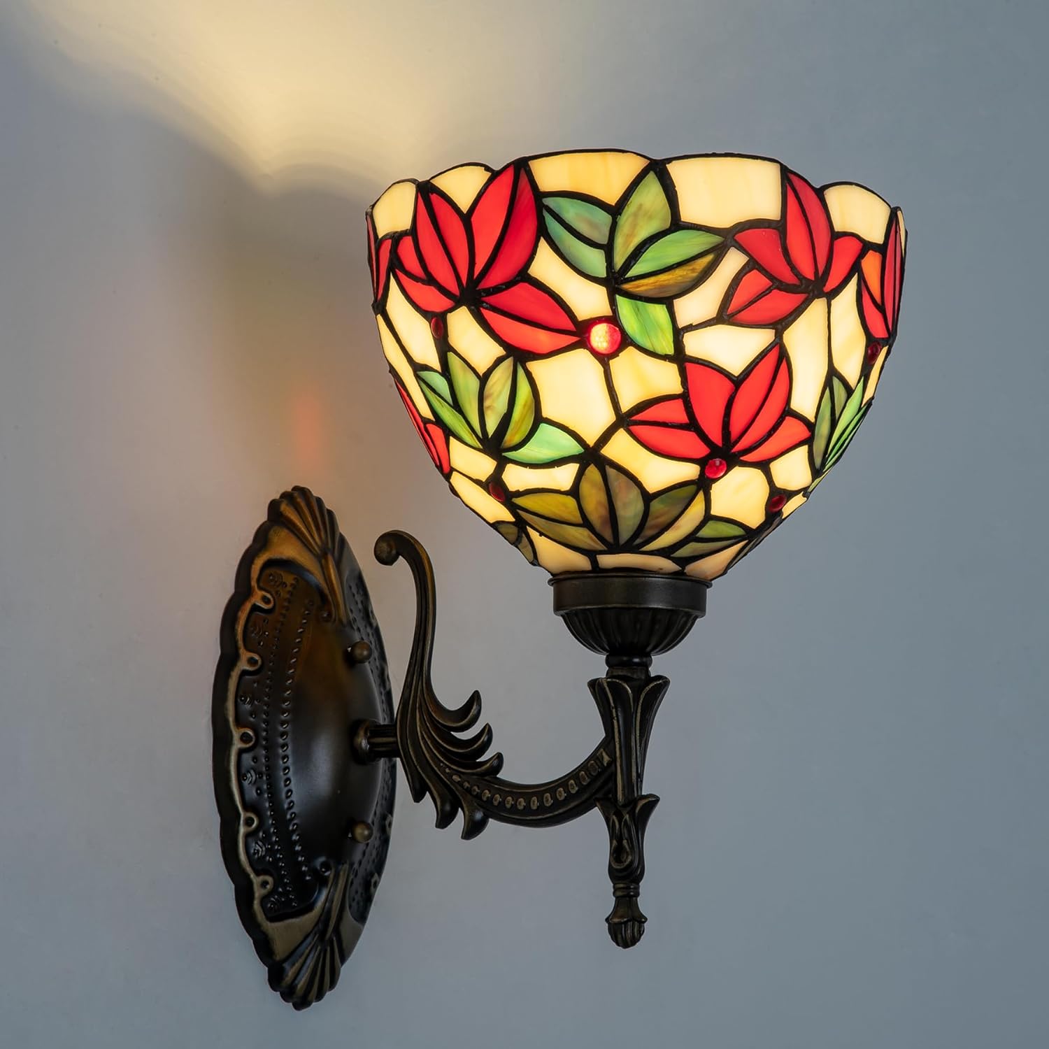 Decorative wall lamp with stained glass shade featuring red and green leaves on a gray background.