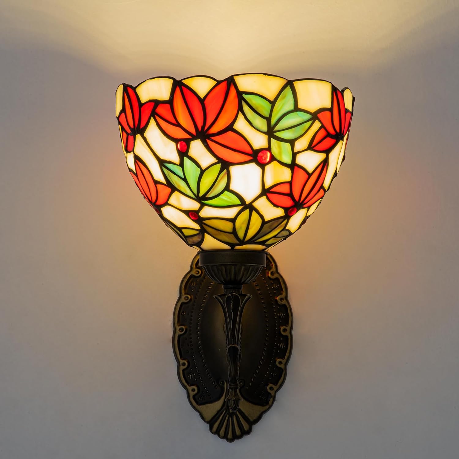Decorative wall lamp with stained glass shade featuring leaf patterns on a plain background.