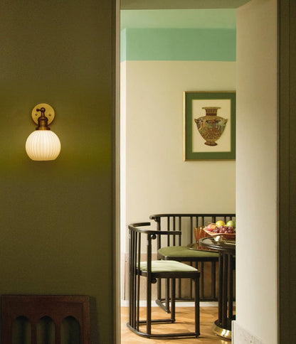 Dining room with a wall sconce, table, and chairs.