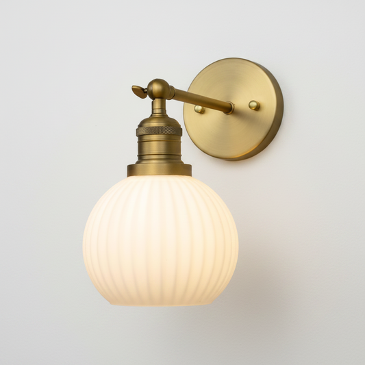 Brass wall sconce with a glass shade on a white background