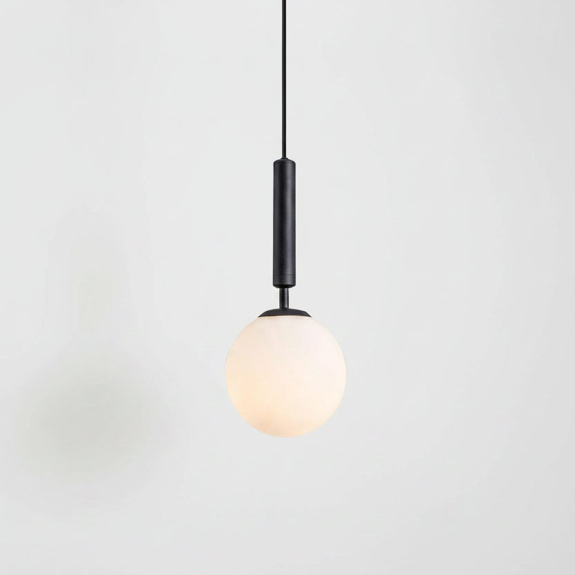 Two black pendant lights with spherical frosted white glass shades hanging over a modern white kitchen. A larger close-up of one light is shown on the left, and the other is shown in situ on the right.