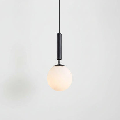 Two black pendant lights with spherical frosted white glass shades hanging over a modern white kitchen. A larger close-up of one light is shown on the left, and the other is shown in situ on the right.