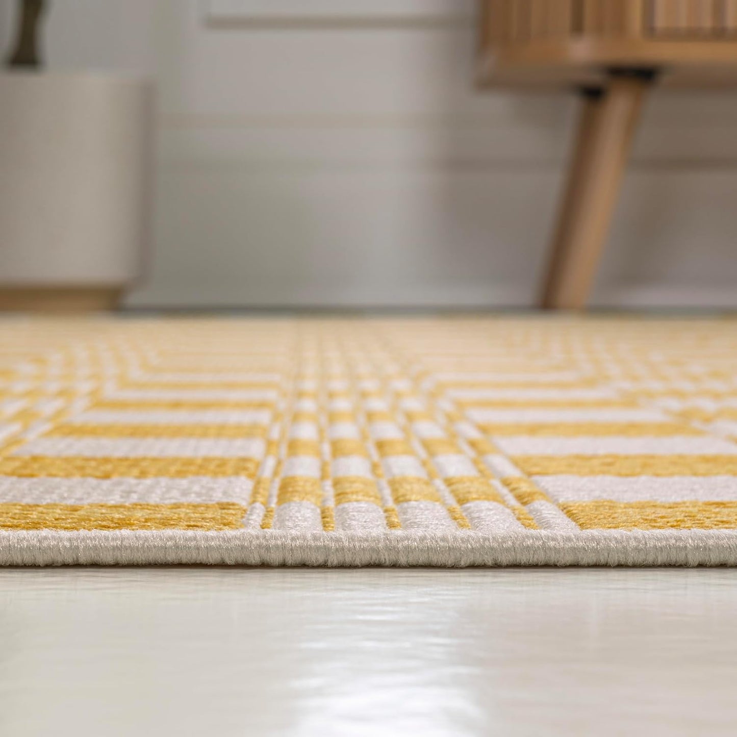 Yellow and gray geometric patterned rug on a wooden floor.