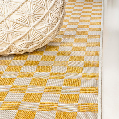 Close-up of a yellow and white checkered rug with a woven basket on top.