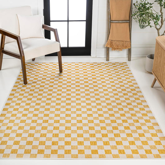 Checkered yellow and white rug in a room with a chair and plant.