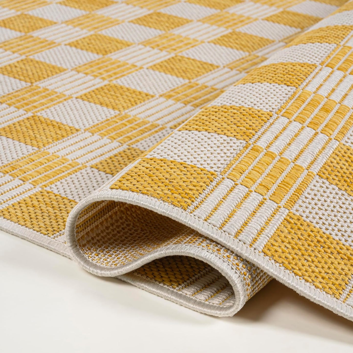 Yellow and beige checkered patterned rug on a plain background