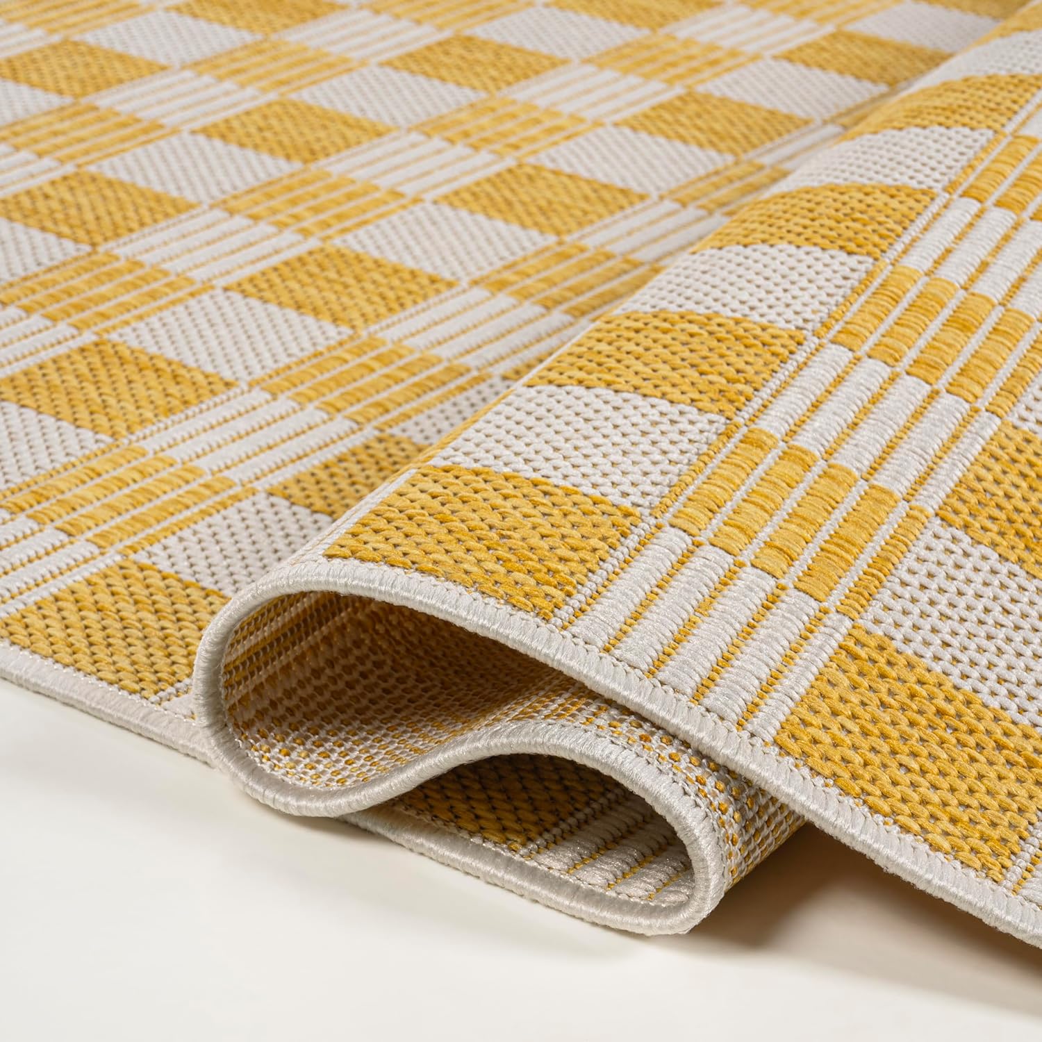 Yellow and beige checkered patterned rug on a plain background