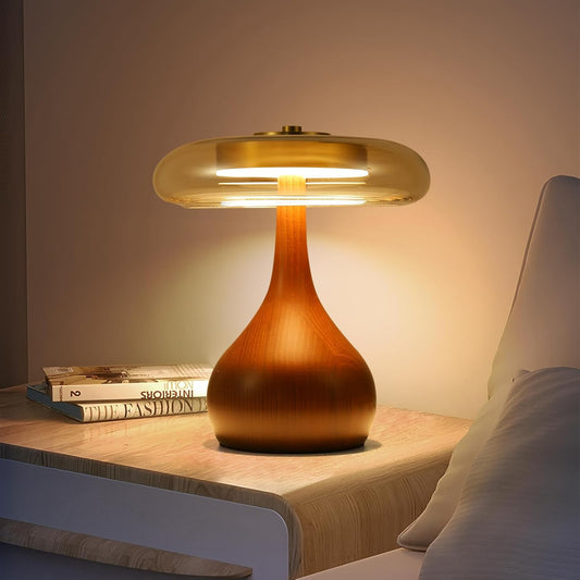 Wooden table lamp on a nightstand with books and pillows in the background