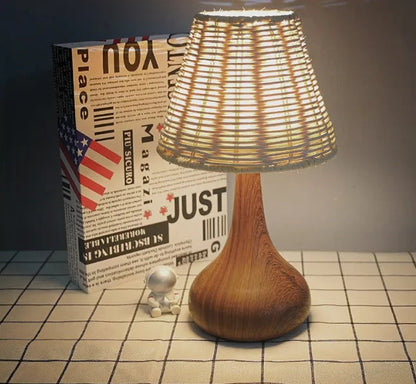 Wooden table lamp with wicker shade on a checkered floor next to a box.