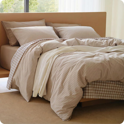Neatly made bed with beige and brown striped bedding in a bright room.