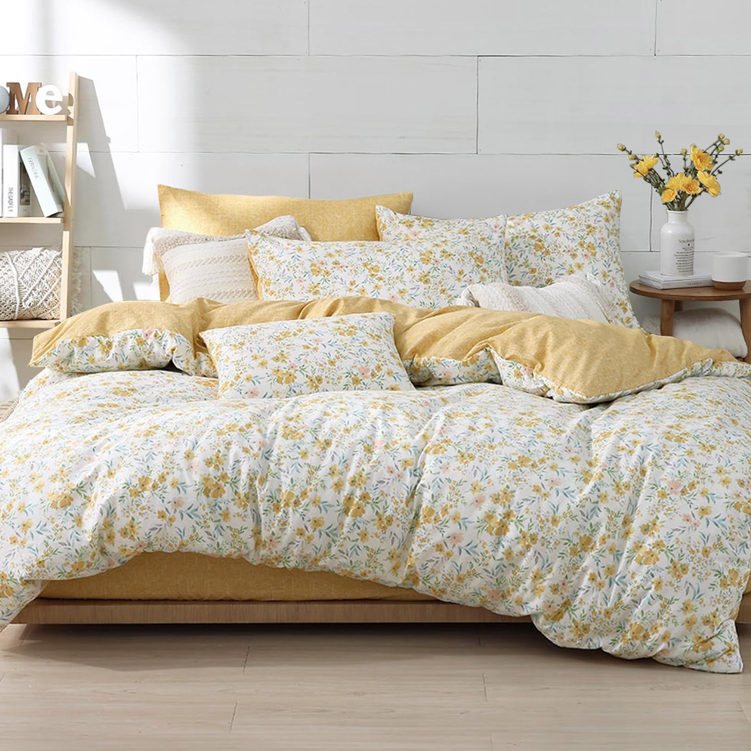 Bed with yellow and white floral bedding in a bright bedroom.