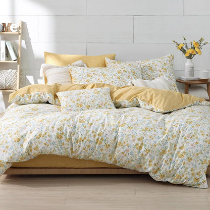 Bed with yellow and white floral bedding in a bright bedroom.