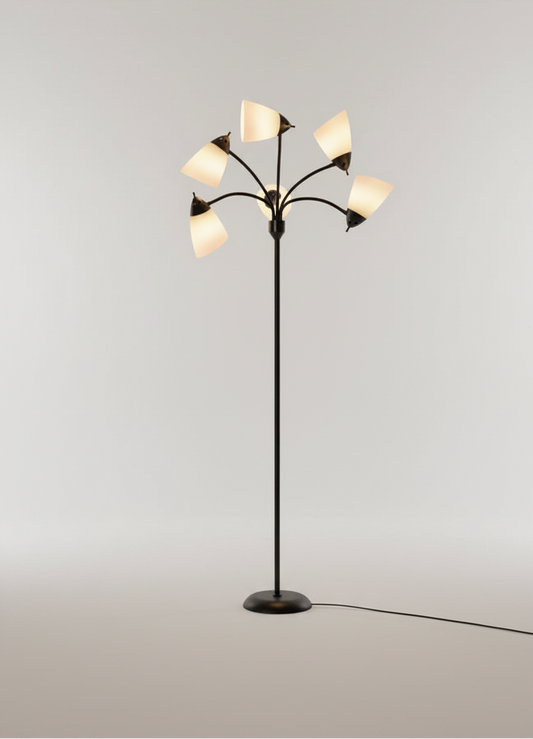 A modern multi-arm floor lamp with a black metal frame and six tapered white shades, shown illuminated against a clean light gray studio background.