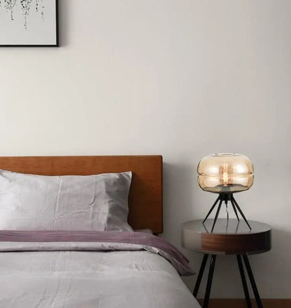 Bedroom with wooden headboard, gray bedding, and a small round table with a lamp.