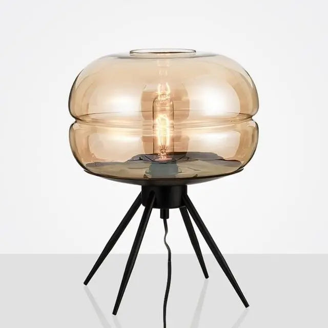 Table lamp with amber glass shade and black metal base on a white background